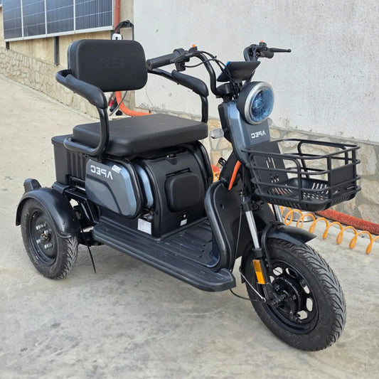 Vedere din față stânga a tricicletei electrice model sport, culoare gri, cu coș frontal și 3 locuri reglabile.